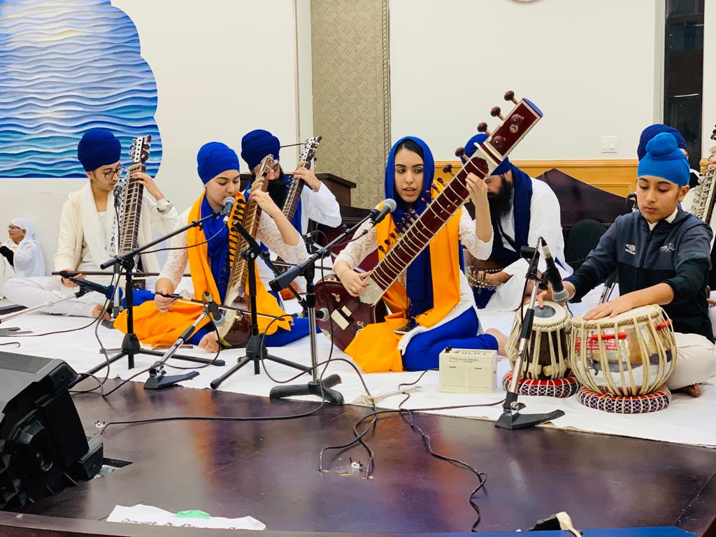 Students playing stringed instruments and tabla on a stage
