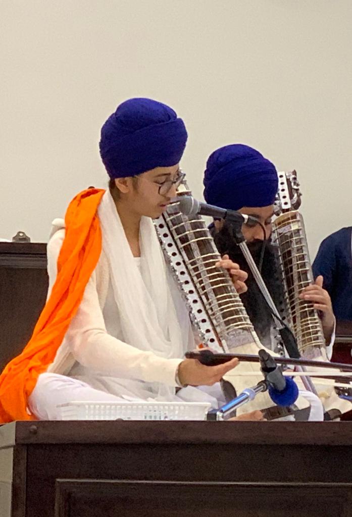 Young musician singing at a microphone while playing the harmonium