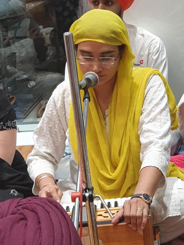 Woman singing at a microphone while playing the harmonium