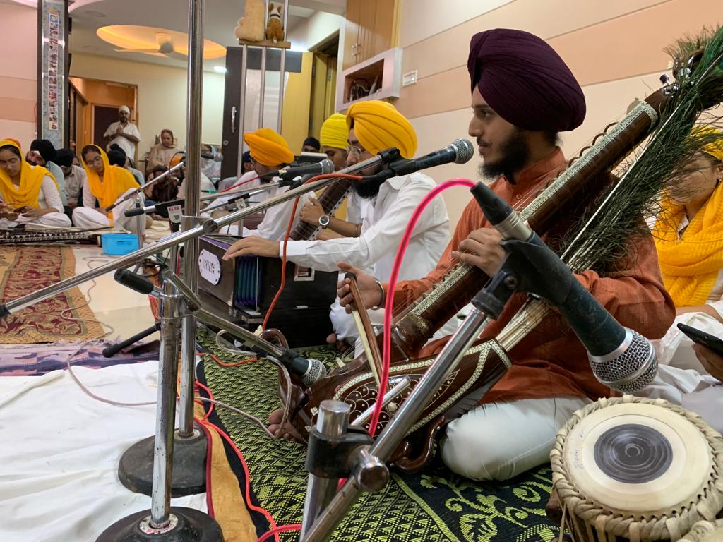 Musician playing a bowed instrument with a tabla in the foreground
